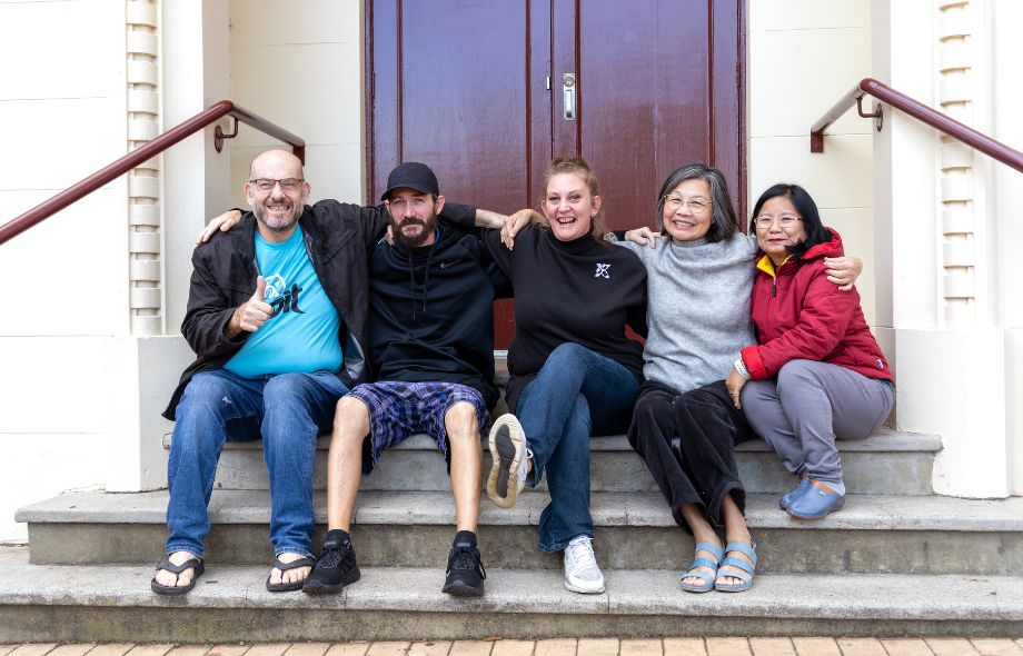 Members of River’s Peer Advisory Group sitting together on steps, celebrating their first anniversary.